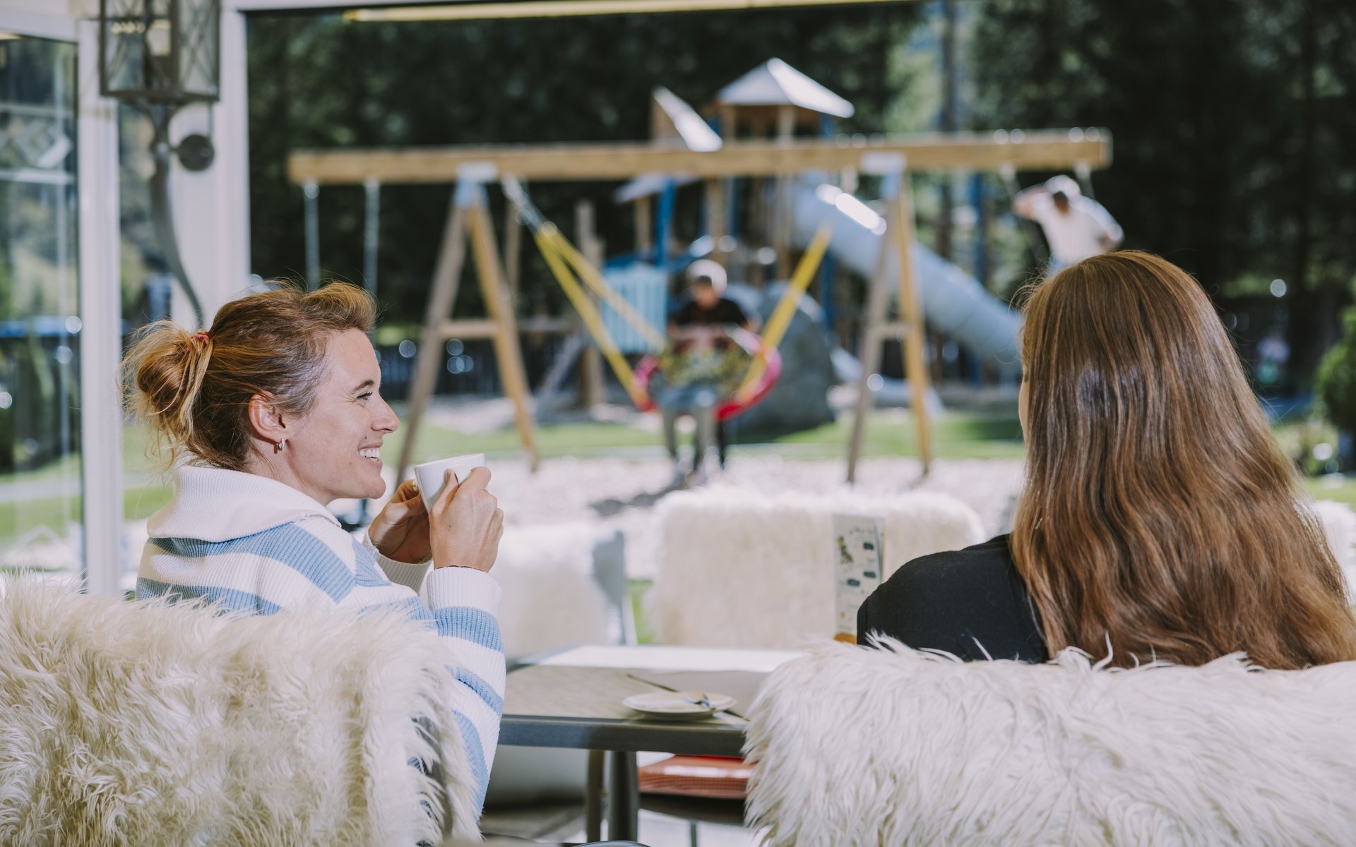 Familie auf eine Terrasse mit Blick auf den Spielplatz