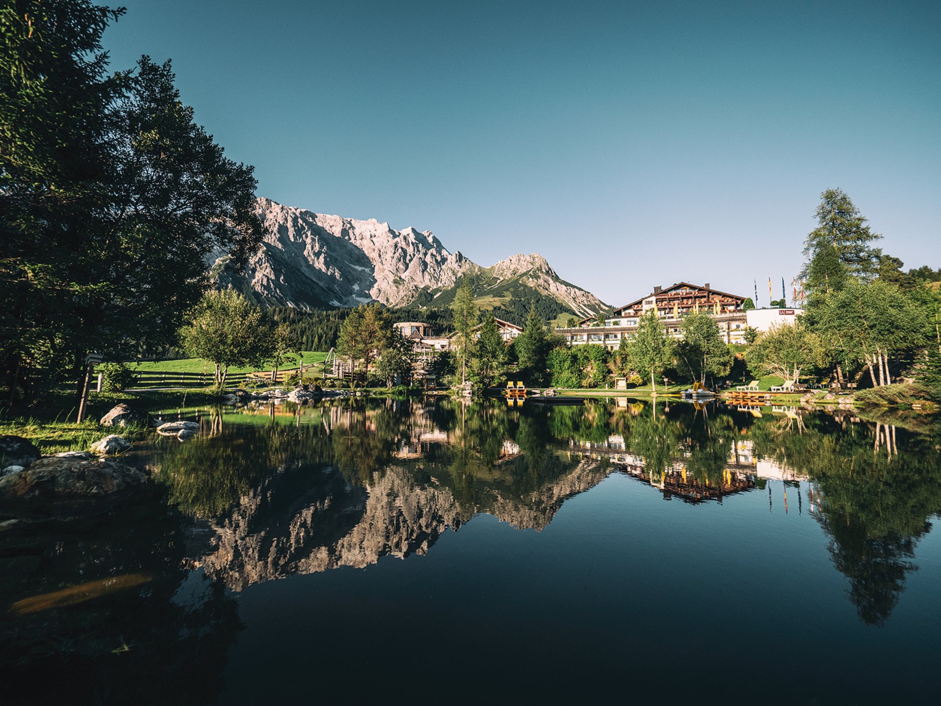 Bergsee mit einer Spiegelung der Berge vor dem Hotel